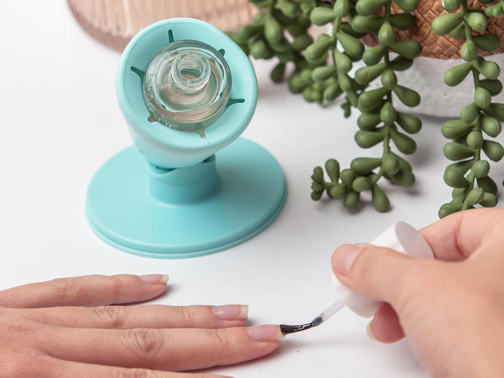 A Zen Green Hinge on a white wall holding a clear polish bottle while a hand paints