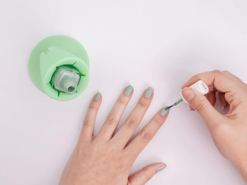 A hand painting nails while a green Hinge holds the polish bottle